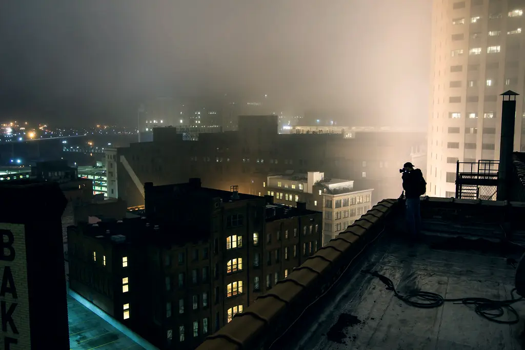 Brandon photographing a foggy Cleveland from a rooftop