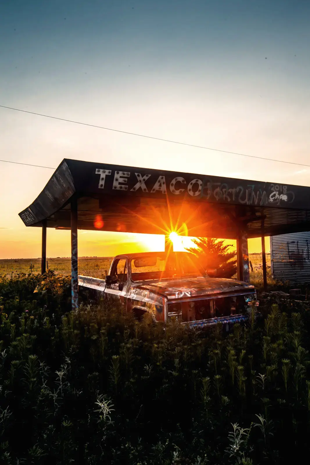 An old graffiti covered pickup truck at sunset at an abandoned building along Route 66