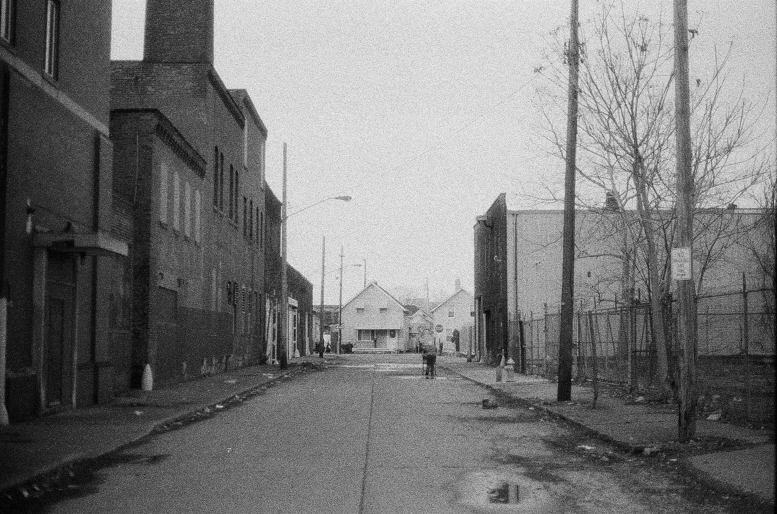 A black and white photo of an old man with a walker in an alley on Cleveland's west side