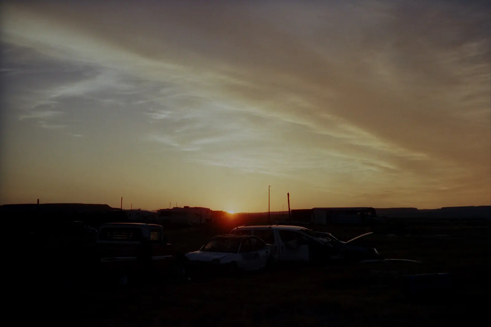 Sunset behind abandoned cars at a ghost town in Utah